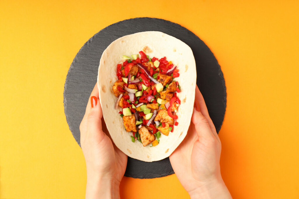 Tabla de tacos preparados con tortillas Todus sobre fondo naranja